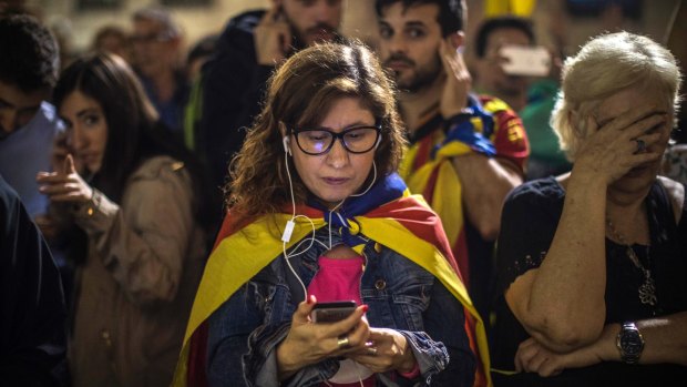 People listen on their phones to Catalan President Carles Puigdemont's speech outside the Palau Generalitat in Barcelona on Saturday.