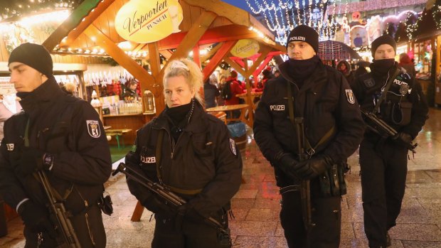 Heavily armed police walk through the reopened Breitscheidplatz Christmas market, the site of the deadly attack.