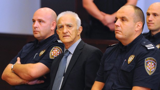 Dragan Vasiljkovic, center, sits between two guards in a courtroom at the beginning of his trial.