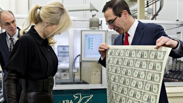 Steven Mnuchin, US Treasury secretary, right, displays an uncut sheet of $US1 dollar notes bearing Mnuchin's name for his wife Louise Linton.