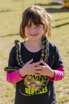Zoe McLaren, 6, with  a snake as part of the reptile display at the Googong Fishing Fair.