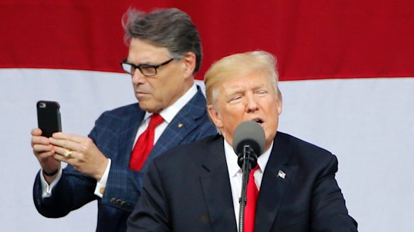 Perry uses his phone while Trump delivered a speech on Monday.