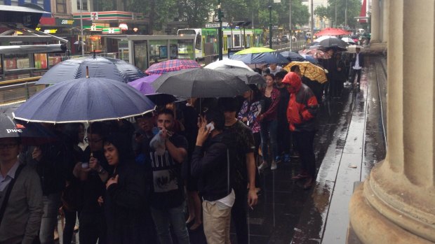 Shoppers queue in the rain along Elizabeth Street. 