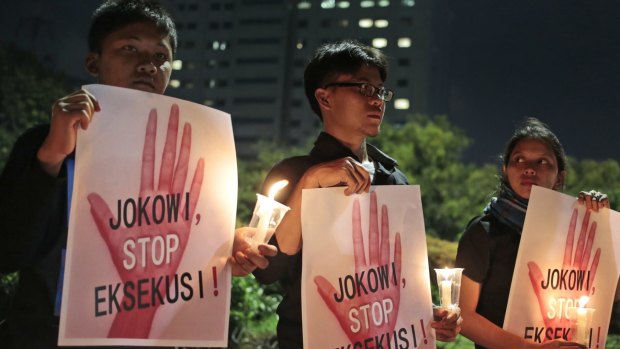 Activists hold posters which read "Jokowi, stop the executions!" during a candlelit vigil outside the presidential palace in Jakarta.
