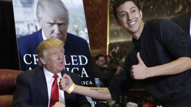 Jason Szkup of Leivittown, New York, shows his "Trump 2016" tattoo to Republican presidential candidate Donald Trump as Trump autographs copies of his new book at Trump Tower, in New York.