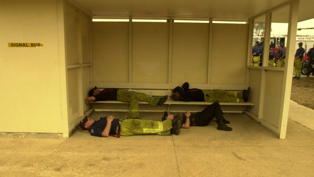 Firefighters catch up on some rest in a bus shelter in Hindmarsh Drive in Duffy on Monday, January 20, 2003. 