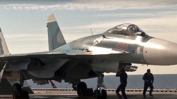 A Russian Su-33 fighter jet stands on the flight deck of the Admiral Kuznetsov aircraft carrier.