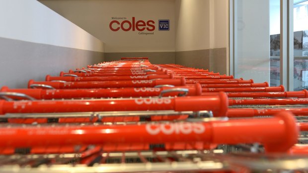 Rows of shopping trolleys stand at a Coles supermarket.