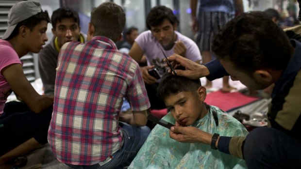 A boy gets his hair cut at a refugee and migrant camp inside Keleti train station in Budapest, Serbia.