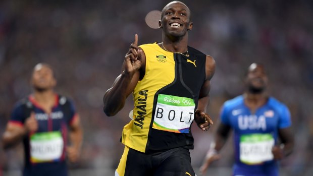 Three-time champion: Usain Bolt celebrates winning the 100m final, with Justin Gatlin, right, finishing second.