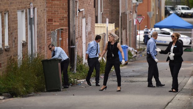 NSW police officers search the crime scene on Price Lane in Riverwood.