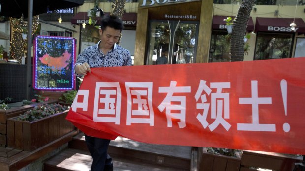 A worker of a restaurant bar puts up a banner which partly reads: "South China Sea is China's territory" in Beijing.