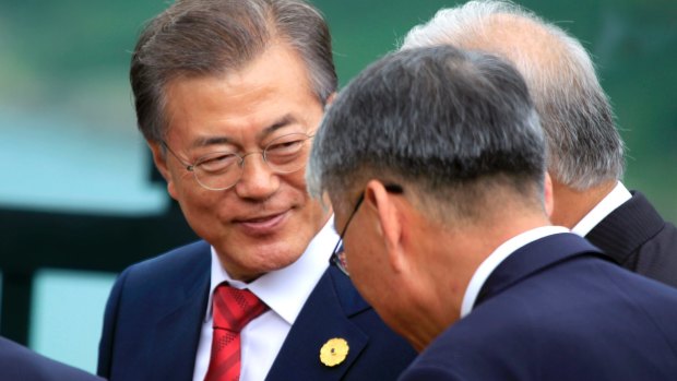 South Korean President Moon Jae-in talks with other leaders before an APEC photo call on Saturday.