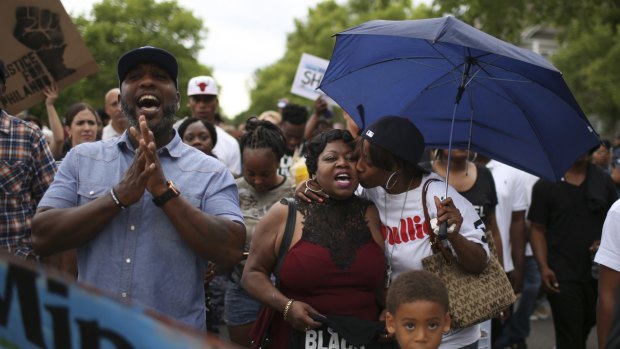Valerie Castile, centre, the mother of Philando Castile, is kissed by her son's girlfriend, Diamond Reynolds, as they lead marchers from the J.J. Hill Montessori Magnet School to the Minnesota governor's home. 