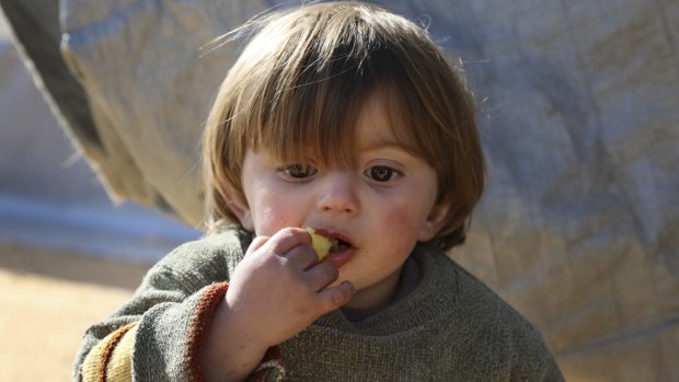 A displaced Syrian boy eats at a temporary refugee camp in northern Syria, near the Bab al-Salameh border crossing with Turkey.