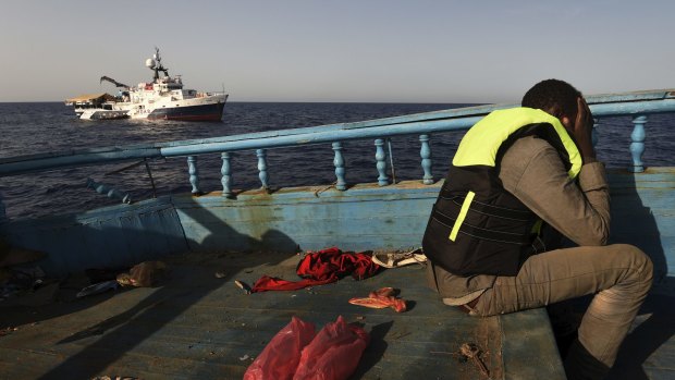 A refugee sits in despair on a wooden fishing boat as he waits to be rescued off the coast of Libya. 