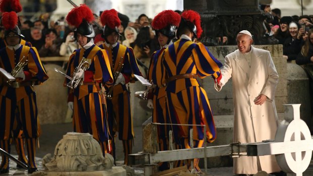 Pope Francis shakes hands with a Swiss guard as he passes among debris from recent Central Italy quake that were placed next to the nativity scene.