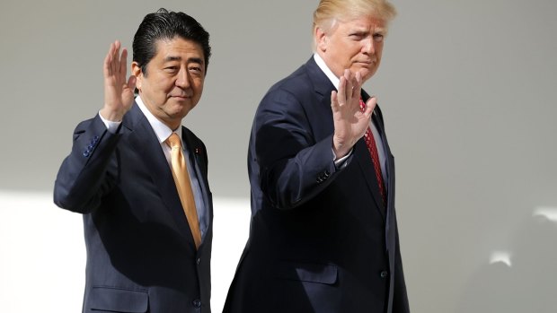 Donald Trump and Shinzo Abe wave while walking to a joint news conference.