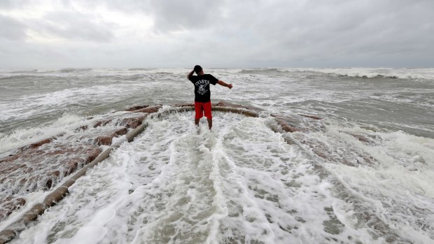 Luis Perez watches waves crash again a jetty in Galveston, Texas.