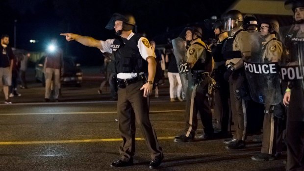 August 2015: Police on the streets of Ferguson, Missouri, during demonstrations the night after an 18-year-old black man, Tyrone Harris, was shot and wounded by police during protests marking the first anniversary of the fatal police shooting of Michael Brown. 