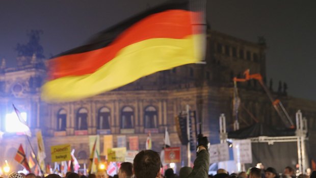 Supporters of the Pegida movement, including a man waving a German flag, gather on October 19, on the first anniversary of the first Pegida march.