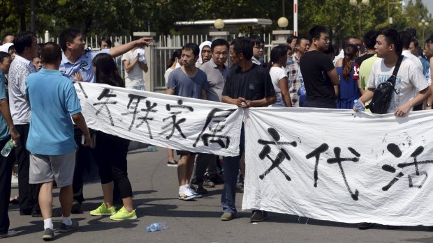 A policeman gestures as he tries to stop relatives, mostly of missing firefighters, from unfurling a banner during a protest to demand information about those missing.