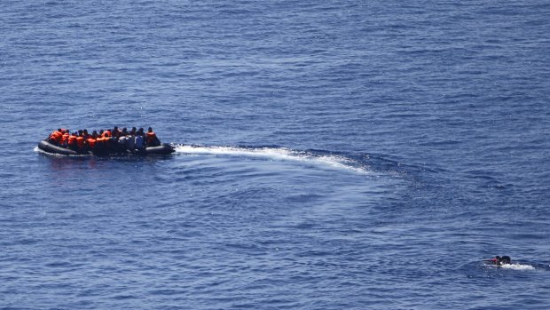 A man tries to swim towards a dinghy carrying migrants as it leaves for the Greek island of Lesbos on Thursday.