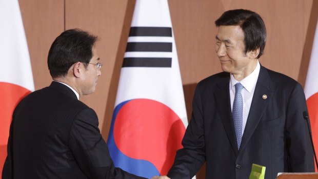 South Korean Foreign Minister Yun Byung-Se (right) shakes hands with Japanese Foreign Minister Fumio Kishida after a joint news conference.