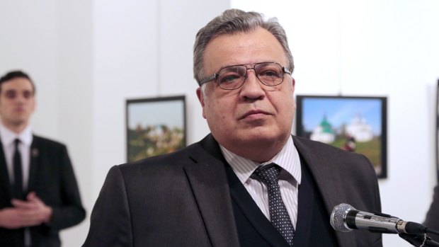 Andrei Karlov pauses during his speech, moments before Mevlut Mert Altintas, seen in the background, shoots him.