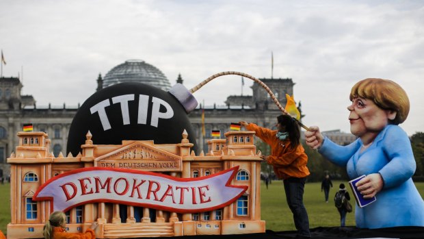 The organisation Food Watch demonstrates with a replica of the Reichstag and a figure depicting German Chancellor Angela Merkel against the Transatlantic Trade and Investment Partnership in front of the Reichstag building in Berlin.