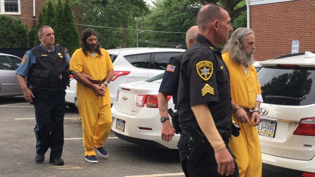 Daniel Stoltzfus, left in yellow, and Lee Kaplan, right in yellow, are led to a preliminary hearing outside Bucks County Magisterial District Judge John I. Waltman's courtroom in Feasterville, Pennsylvania.