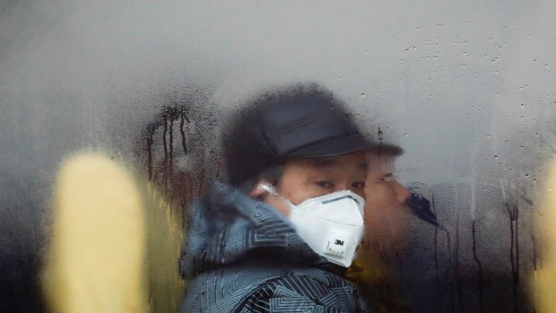 A man wearing a mask looks out from a bus in Beijing as the capital of China is blanked by smog. 