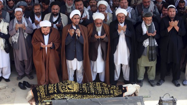 Afghan men offer funeral prayers behind the body of civilian killed in Friday night's suicide attack at the Shiite mosque.