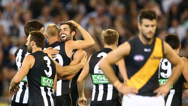 Disappointment for Tigers skipper Trent Cotchin as the Magpies celebrate on Friday night.