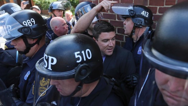Unite the Right rally organiser Jason Kessler is escorted by police after his press conference was disrupted by protesters on Sunday.