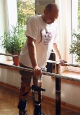 Darek Fidyka walks with the assistance of parallel bars and leg braces.