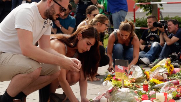 People lay flowers and candles outside the OEZ shopping centre. 