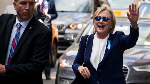 Democratic presidential candidate Hillary Clinton waves as she walks from her daughter's apartment building on September 11, 2016, in New York, two hours after the incident.