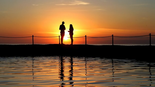 A couple take in the sunrise at Cronulla Rock pool.