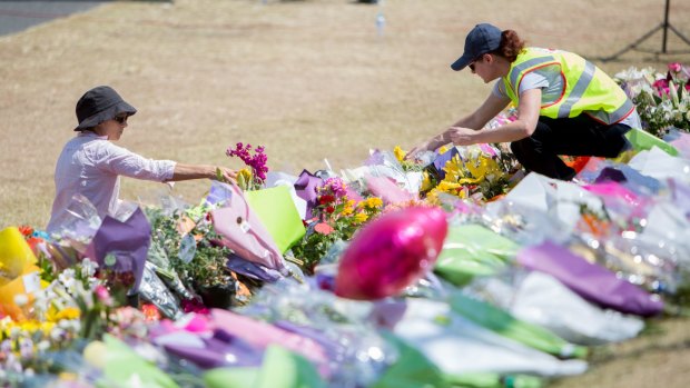 People lay tributes at Dreamworld while a private memorial service was held inside on Friday.