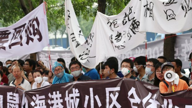 Tianjin residents evacuated from their homes take part in a rally outside a government press conference.