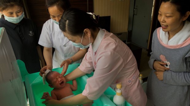 Ms. Li watches nurses bathe her baby son at Red Wall Maternity Care Center.