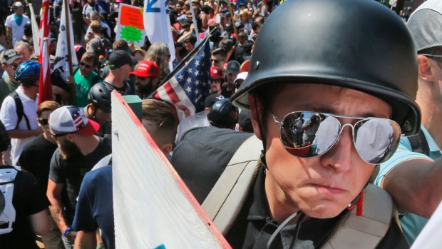A white nationalist demonstrator with a helmet and shield marches in Charlottesville. Death and injury marked the weekend clashes between neo-Nazis and their opponents.