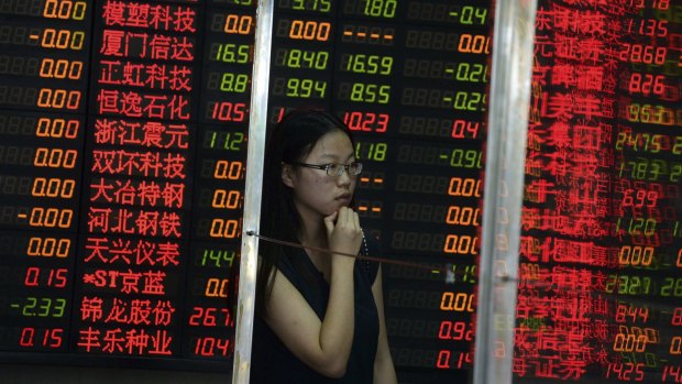 A Chinese woman stands behind a glass panel near stock prices displayed on a board at a brokerage house in Shanghai, China.
