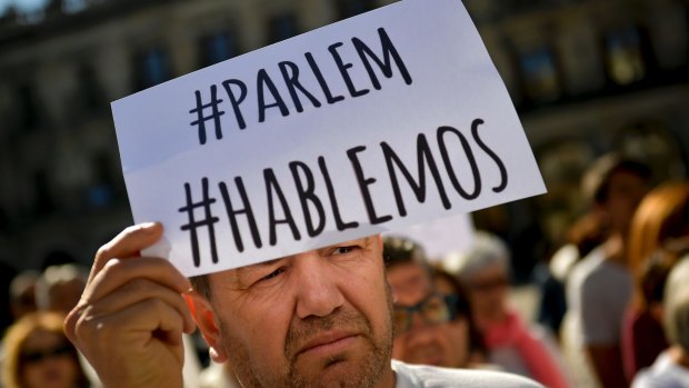 A man holds up sign reading in Spanish and Catalan language, ''We Talk'', as he takes part in a rally calling to find a solution for the crisis with Catalonia's secession at Plaza Espana square, in the Basque city of Vitoria in northern Spain.