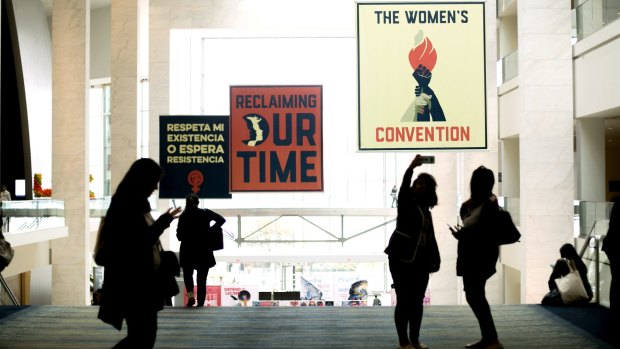 Attendees take a selfie photograph in front of signage displayed during the Women's Convention in Detroit, Michigan.