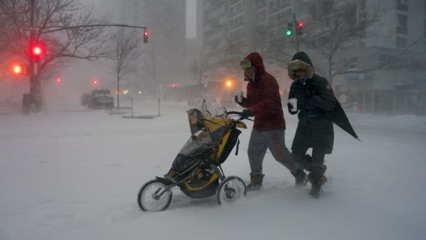 Sean Jackson and Gina Del Tatto push their child, Hayes Jackson, in a stroller as heavy snow falls in New York's Upper West Side.