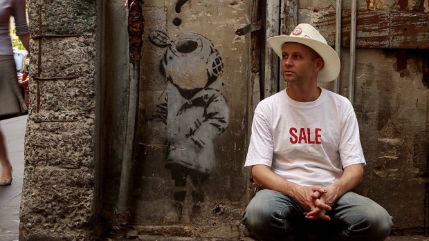 Street art expert Andrew McDonald next to an original Banksy in one of Melbourne's lanes.  
