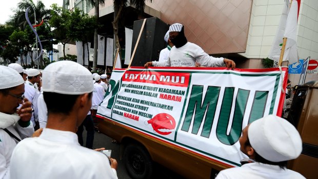 Islamic hardliners rally outside a shopping centre in Surabaya with a sign drawing attention to a fatwa issued by the Majelis Ulema Indonesia (MUI), an Islamic scholarly body, against Muslim staff wearing Christmas hats.