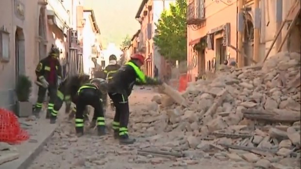 Firefighters begin to move rubble from a damaged building in Norcia, Italy, on Sunday.
